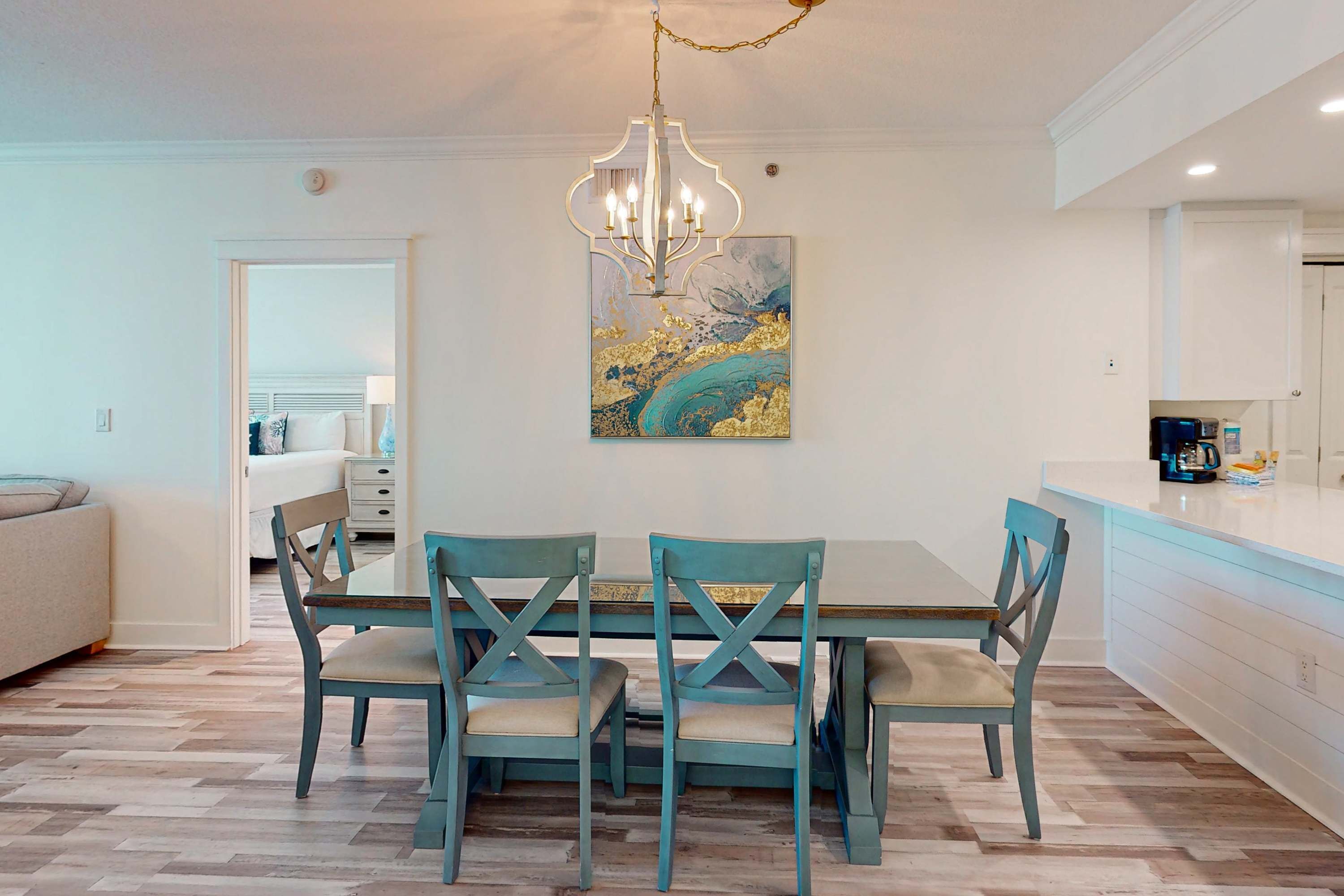 A dining area with a table and chairs, a chandelier, and a painting on the wall.