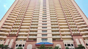 A high-rise hotel with multiple balconies and a central entrance. - 12th-floor, waterfront condo with pools, grills & fitness center (Panama City Beach)