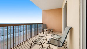 A balcony with a view of the ocean, metal chairs, a table, and a TV. - 12th-floor, waterfront condo with pools, grills & fitness center (Panama City Beach)