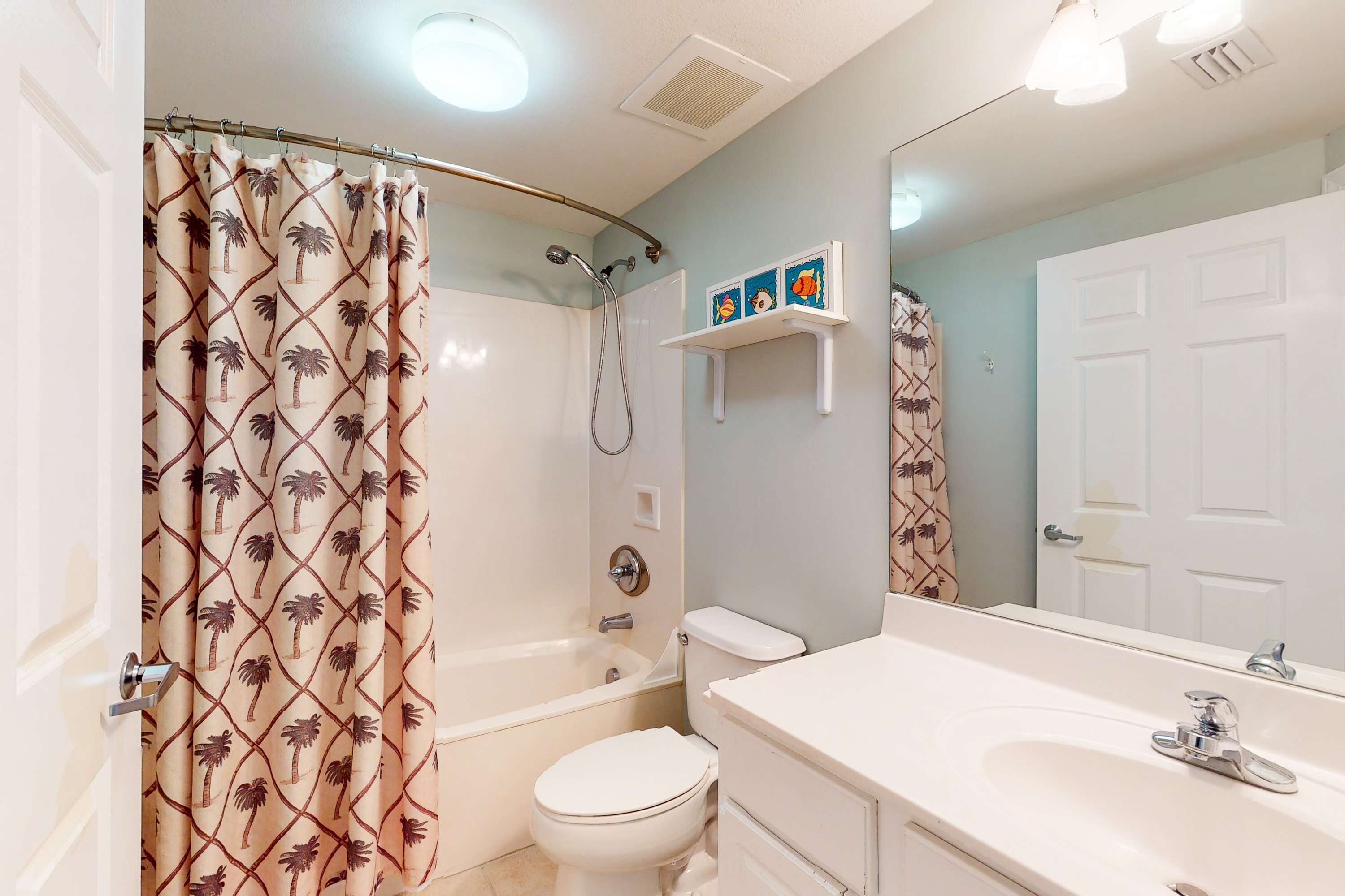 A bathroom with a shower curtain, toilet, bathtub, sink, and a mirror.