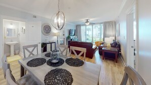 A modern living room with a dining area, a red sofa, a coffee table, and a chandelier. - Handicap accessible ground-floor condo on Okaloosa Island Waterfall, Lazy River (Fort Walton Beach)