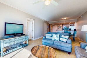 A living room with a TV, sofa, and a dining area with chairs. - Spacious, Beachy Condo At Waterscape Children's Playground, 2 Hot Tubs (Fort Walton Beach)