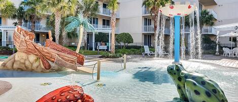 A pool area with a frog statue, a ship sculpture, and a water fountain.