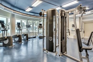 Ein Fitnessraum mit unterschiedlichen Trainingsgeräten, darunter Laufbänder, ein Krafttrainer und eine Bank.