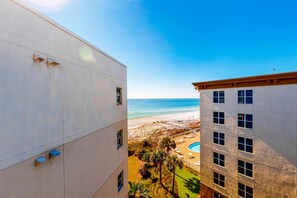 Vista de un edificio con piscina y playa al fondo.