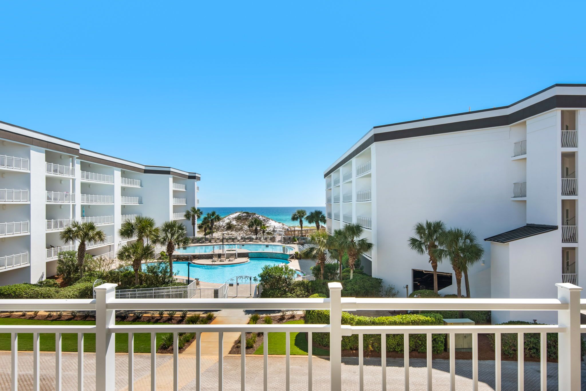 A resort with a pool, palm trees, and a view of the ocean.