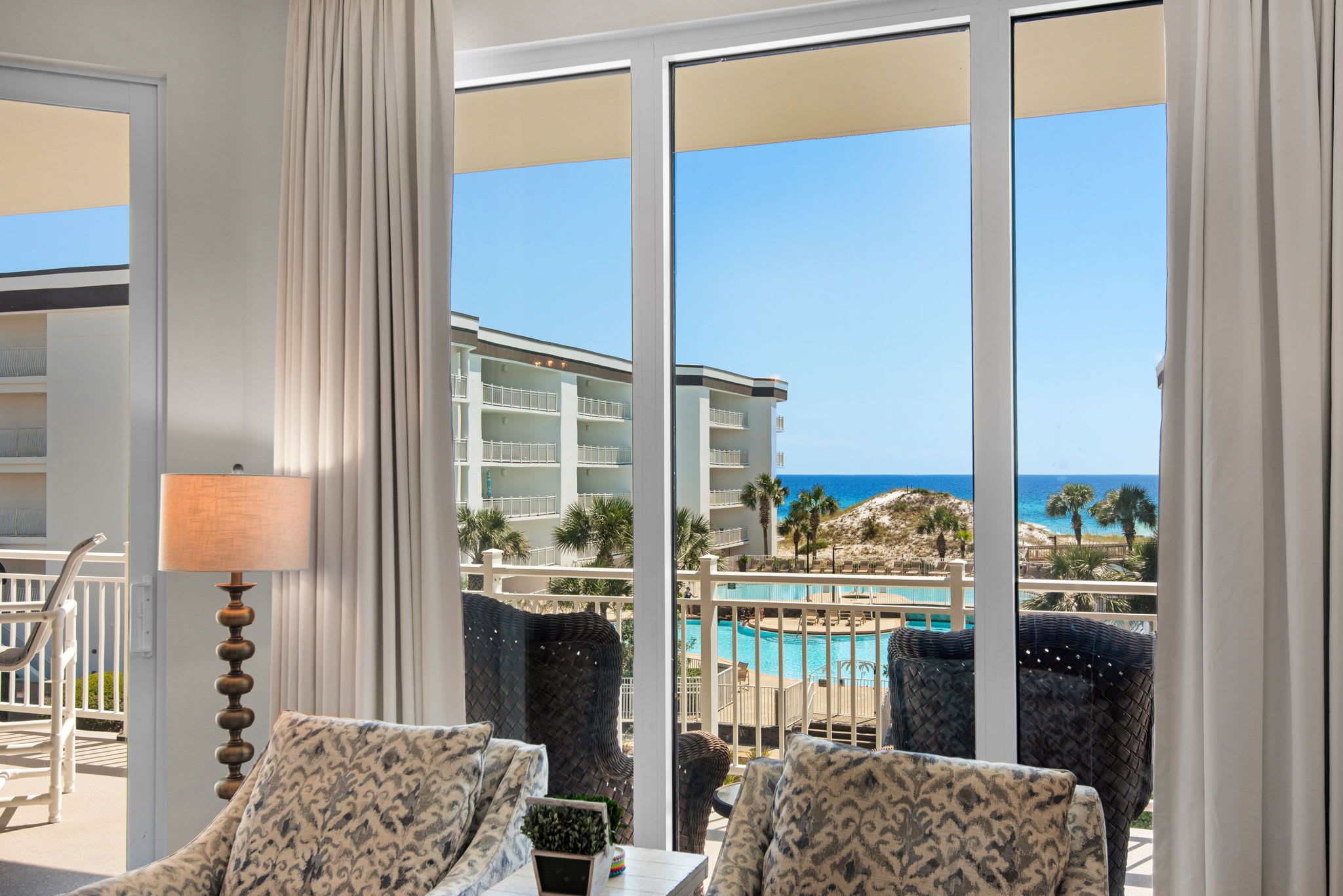 A hotel room with a view of a pool and a building across the street.