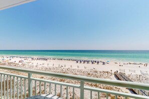 A beach view from a balcony with a railing, sandy beach, and ocean. - Gorgeous and cozy beachfront condo with shared pool and beach access (Fort Walton Beach)