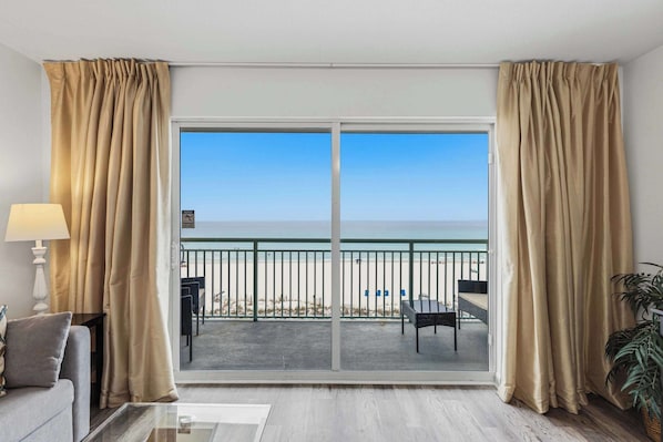 A room with a large sliding glass door leading to a balcony with a view of the beach. - Gorgeous and cozy beachfront condo with shared pool and beach access (Fort Walton Beach)