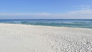 Een strand met wit zand en kalm blauw water.