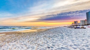 A beach with footprints, a pier, and buildings in the background. - 4th-floor Gulf-front condo with pools - near entertainment (Perdido Key)