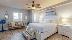 A bedroom with a bed, nightstands, a ceiling fan, a sofa, and a window. - Oceanfront condo with pool, hot tub, central AC, washer&dryer, & fitness room (Fort Walton Beach)