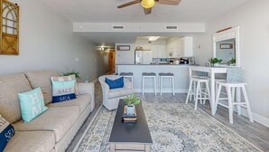 A modern living room with a sofa, coffee table, and a ceiling fan. - Oceanfront condo with pool, hot tub, central AC, washer&dryer, & fitness room (Fort Walton Beach)