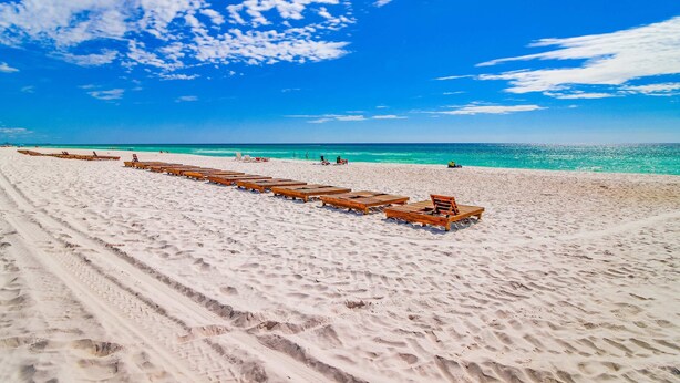 Ein Strand mit in Reihen angeordneten Holzliegen.
