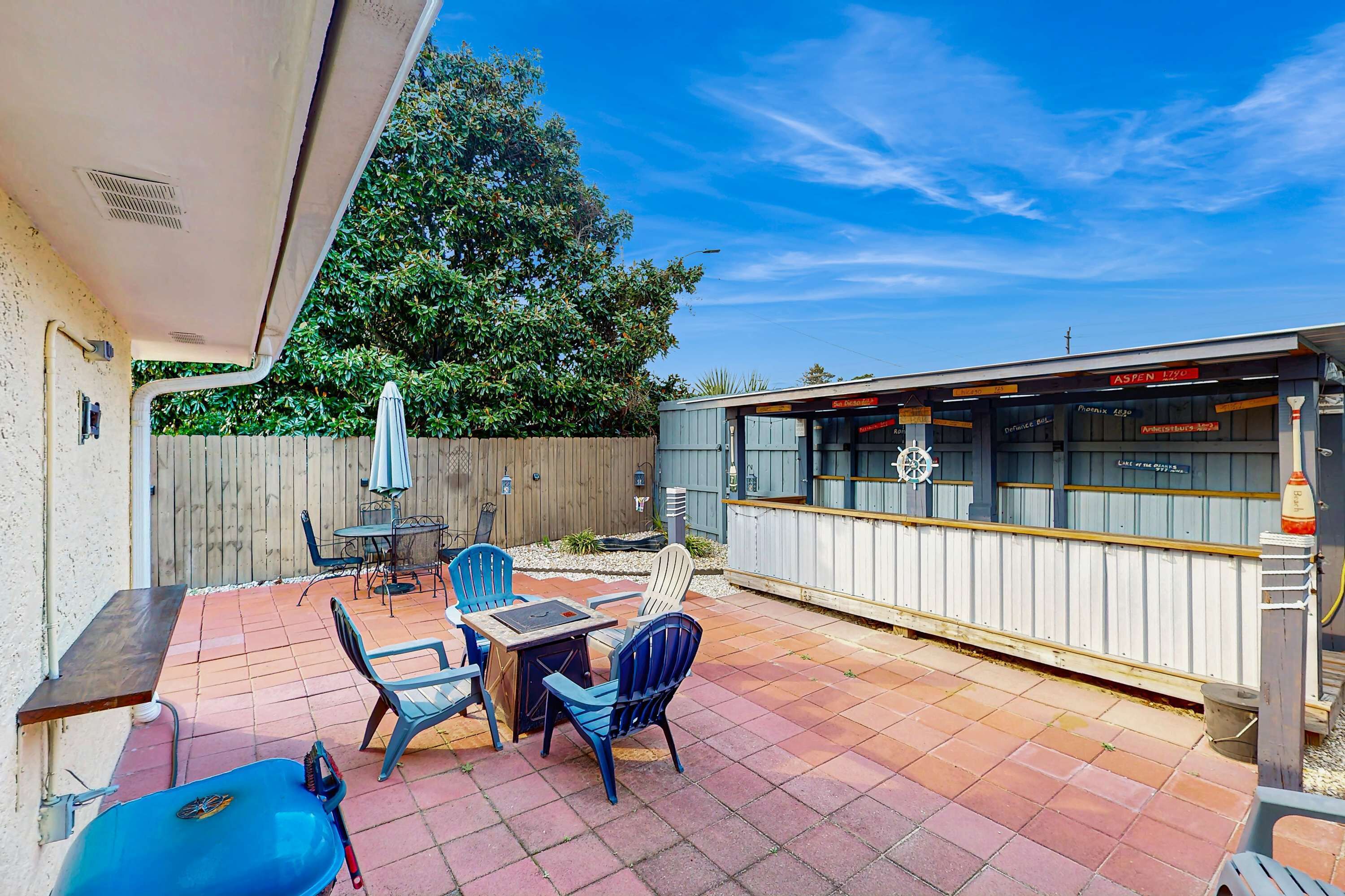 A patio with a table and chairs, a barbecue grill, and a restaurant in the background.