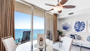 A modern hotel room with a balcony, a ceiling fan, and a view of the ocean. - Gulf-Front Condo w/ 14th-Floor Views, Beach Service & Shared Pools/Hot Tubs (Panama City Beach)