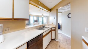 A kitchen with white cabinets, a dishwasher, and a sink. - Cozy condo in paradise with pool, sauna & private dock - snowbird-friendly (Panama City Beach)