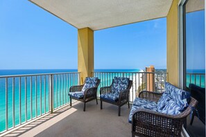 A balcony with wicker furniture, a view of the ocean, and a clear sky. - Beachfront penthouse with 2 free beach chairs, WiFi, amazing views, pool & hot tub (Panama City Beach)