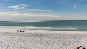 A beach with white sand and a clear blue sky. There are a few people and some beach chairs visible. - Blue Mountain Beach – charming 2nd floor condo with pool view (Santa Rosa Beach)