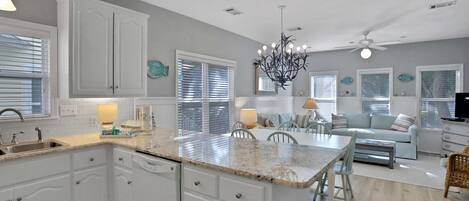 A spacious kitchen with white cabinetry, a granite countertop, and a dining area with a table and chairs.