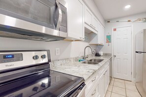 Una cocina moderna con horno Whirlpool, microondas, pileta y muebles de cocina blancos.