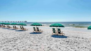 A beach with rows of green umbrellas and wooden lounge chairs. - 5th Floor Elegant, Welcoming Condo At Waterscape Waterfall, Lazy River (Fort Walton Beach)