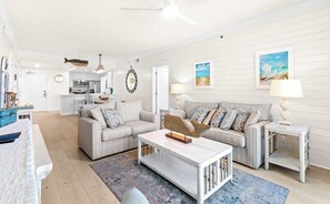 A spacious living room with a sofa, coffee table, and a dining area with chairs and a table. - Gulf front resort with shared pool, beach access, Lazy river, washer&dryer (Fort Walton Beach)