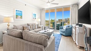 Ein modernes Wohnzimmer mit einer Couch, Sesseln, einem Couchtisch, einem Fernseher und einem Balkon mit Blick.