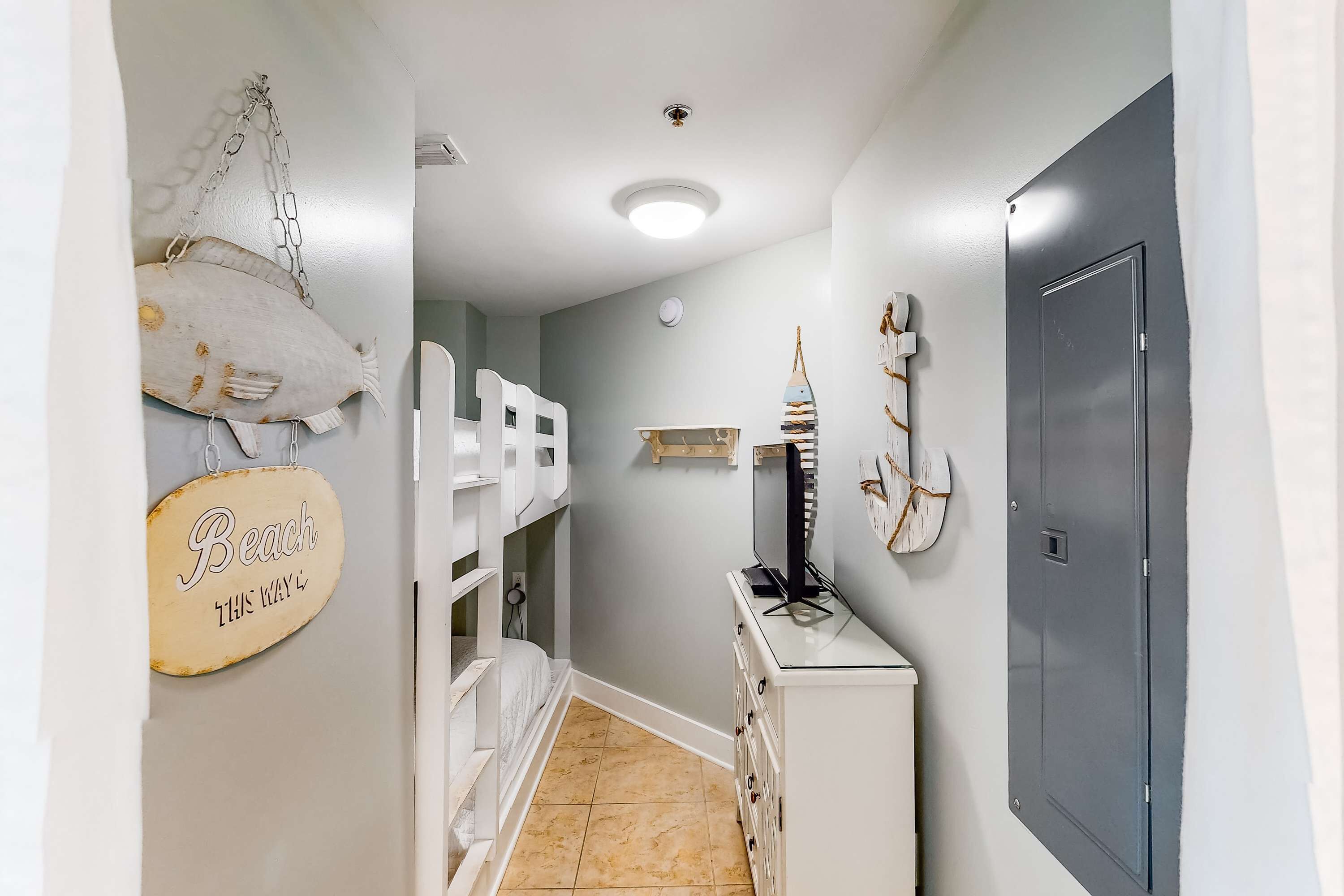 A narrow hallway with bunk beds, a dresser, and a door.