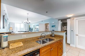 A kitchen with granite countertops, a double sink, wooden cabinets, and a built-in dishwasher. - Picturesque Condo At Waterscape Children's Playground, 2 Hot Tubs (Fort Walton Beach)