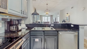 A modern kitchen with a double sink, stainless steel appliances, and a built-in dishwasher. - Gulf-front condo with high-speed WiFi, pools, hot tubs & beach access (Panama City Beach)