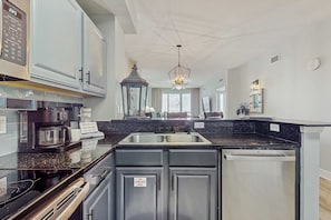 A modern kitchen with a double sink, stainless steel appliances, and a built-in dishwasher. - Gulf-front condo with high-speed WiFi, pools, hot tubs & beach access (Panama City Beach)