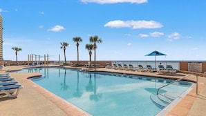 A swimming pool with lounge chairs and palm trees. - Gulf-front condo with high-speed WiFi, pools, hot tubs & beach access (Panama City Beach)