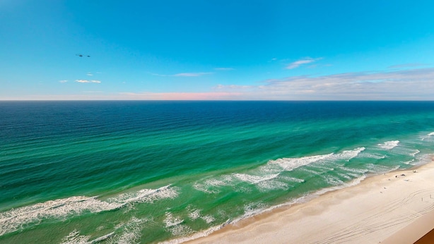 A beach with clear turquoise waters and a sandy shore. - Gulf-front condo with high-speed WiFi, pools, hot tubs & beach access (Panama City Beach)