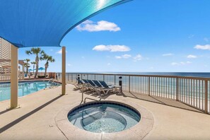 A pool area with lounge chairs, a hot tub, and a view of the ocean. - Gulf-front condo with high-speed WiFi, pools, hot tubs & beach access (Panama City Beach)