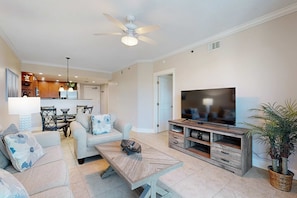 A spacious living room with a sofa set, a coffee table, a TV stand, and a ceiling fan. - Condo in Gulf Front Resort w Shared Amenities w Pool & Hot Tub (Fort Walton Beach)