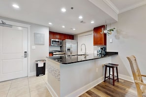 A modern kitchen with a central island, stainless steel appliances, and wooden cabinets. - Sunny Waterscape 6th-floor condo with pools, hot tubs, & stunning Gulf views (Fort Walton Beach)