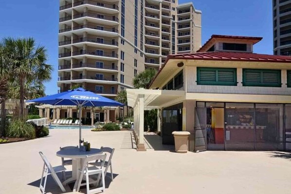 Un hotel con area piscina, posti a sedere all'aperto e un edificio grande sullo sfondo.