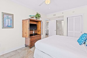 Ein Schlafzimmer mit einem großen Bett, einem Holzschrank, einem Deckenventilator und einer Tür zu einem Badezimmer.