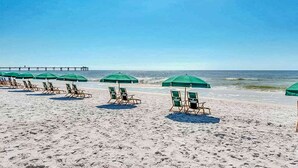 A beach with rows of green umbrellas and lounge chairs. - 3rd Floor Spacious Condo At Waterscape Children's Playground, 2 Hot Tubs (Fort Walton Beach)
