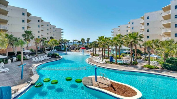 A swimming pool with lounge chairs and palm trees, surrounded by multi-story buildings. - 2nd Floor Waterscape Condo w Beach Access, Beach Service, Shared Amenities (Fort Walton Beach)