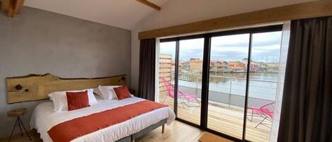 Un dormitorio con una cama grande, un cabecero de madera y vistas a un balcón con sillas.
