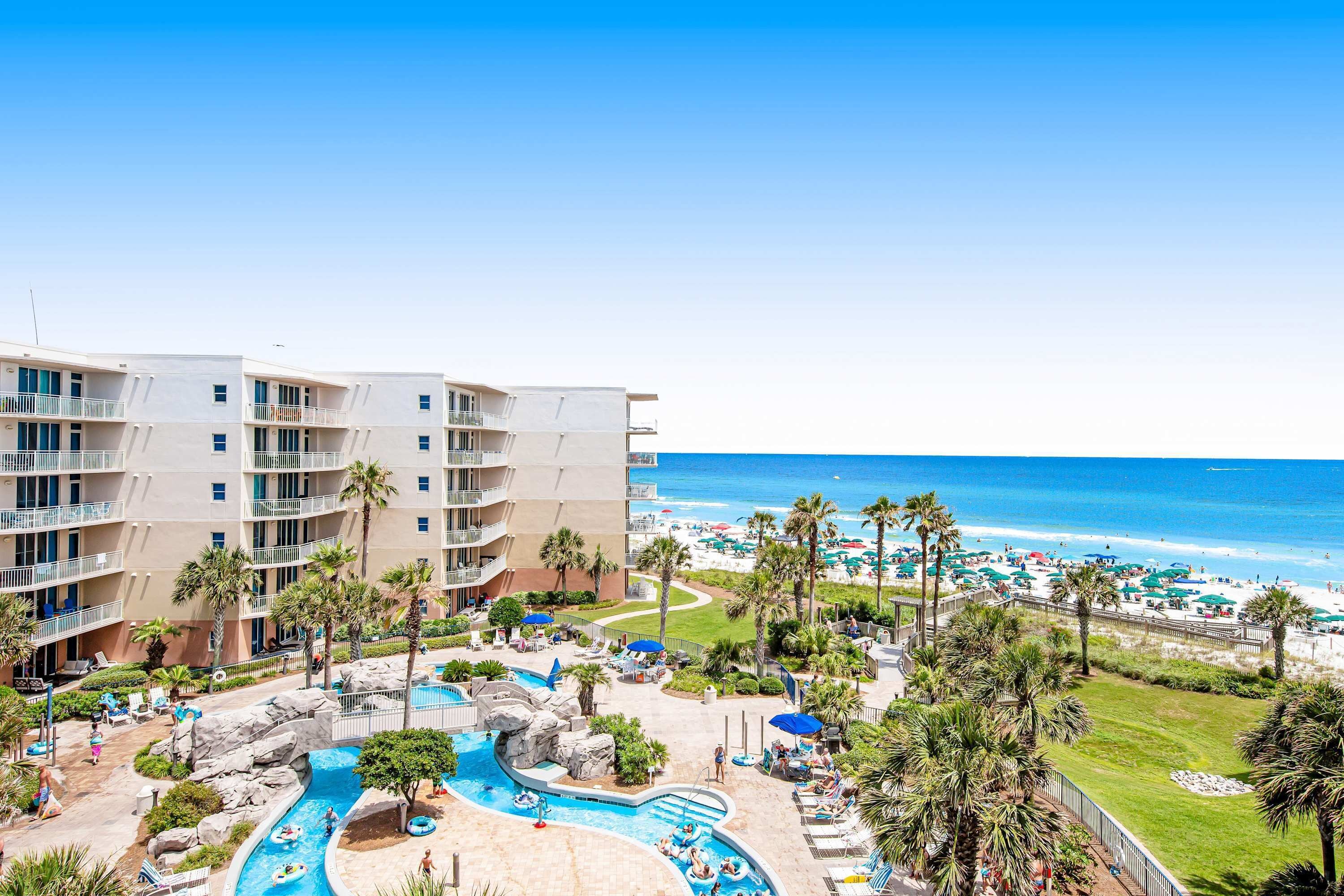 A hotel with a pool area, beach view, and multiple balconies.