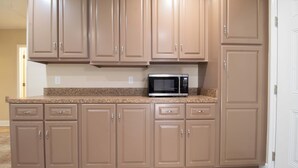 Una cocina con armarios color beige, encimera de granito y microondas integrado.
