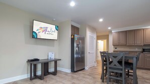 Una cocina moderna con refrigerador empotrado, una mesa de comedor con sillas y un televisor montado en la pared.