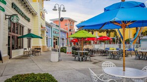 An outdoor café area with tables and chairs, a Starbucks coffee shop, and colorful umbrellas. - Two-story getaway with an indoor pool, patio, washer/dryer, & central AC (Panama City Beach)