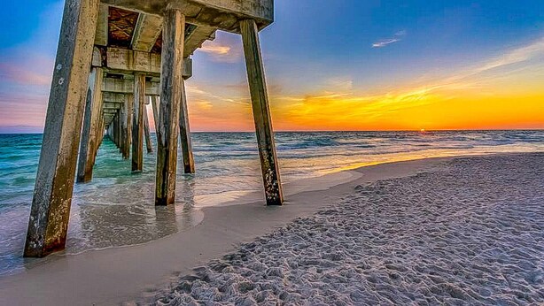 A pier extending into the ocean with a sunset in the background. - Two-story getaway with an indoor pool, patio, washer/dryer, & central AC (Panama City Beach)