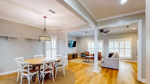 A spacious living area with a wooden floor, white furniture, and a ceiling fan. - Two-story getaway with an indoor pool, patio, washer/dryer, & central AC (Panama City Beach)