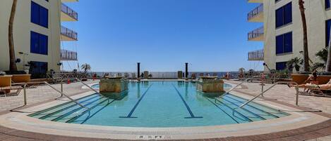 A swimming pool with two lanes, surrounded by palm trees and a view of the ocean.