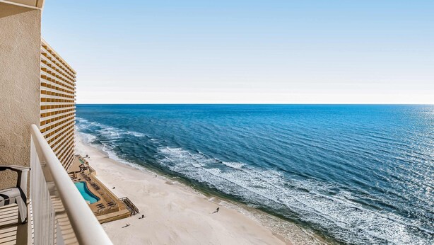 Um hotel à beira-mar com piscina, cadeiras de praia e vista para o oceano.